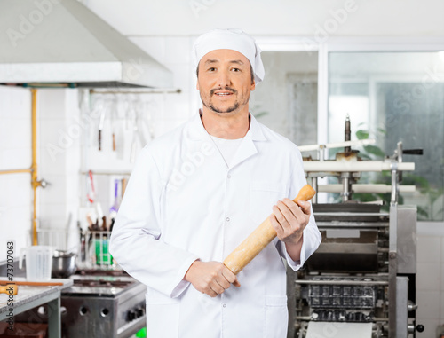 Confident Male Chef Holding Rolling Pin In Kitchen