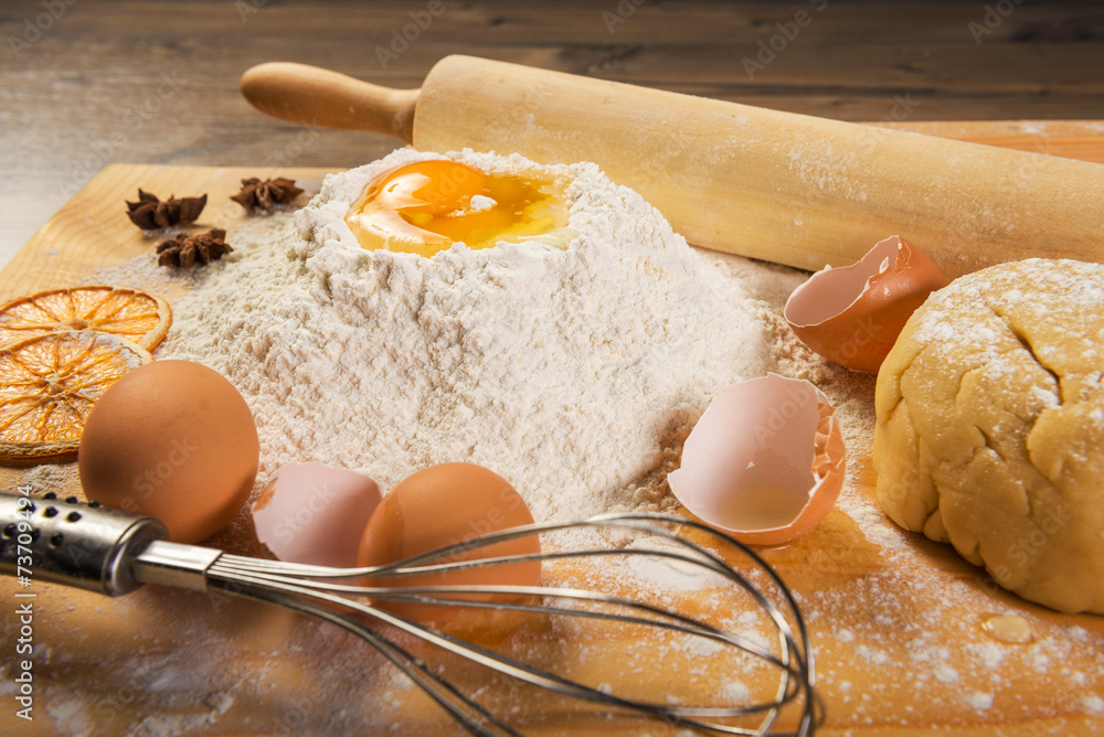 Baking preparation: eggs, flour, rolling pin, spices on a board Baking preparation: eggs, flour, rolling pin, spices on a board