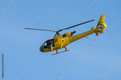 Small yellow private Helicopter in blue Sky
