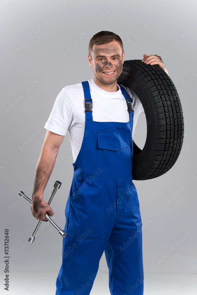 dirty mechanic standing and holding wrench and tire Stock Photo | Adobe  Stock