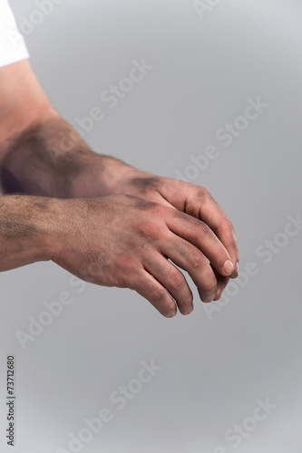 man with dirty hands on grey background.