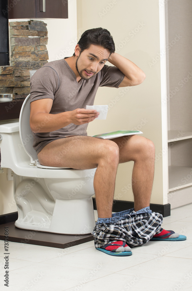 worried man sitting on the toilet running out of paper Stock Photo Adobe Stock