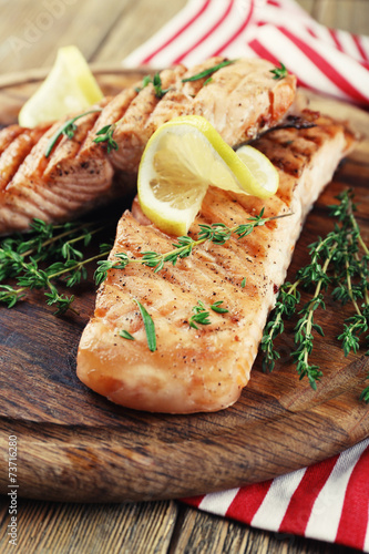 Grilled salmon on cutting board on wooden background