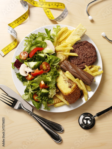 Unhealthy and healthy food, a stethoscope and tape measure