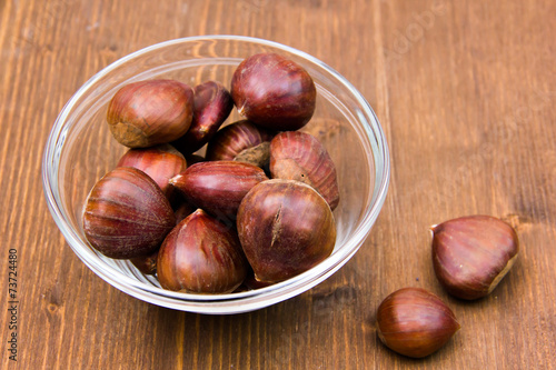 Glass bowl with chestnuts on wooden table