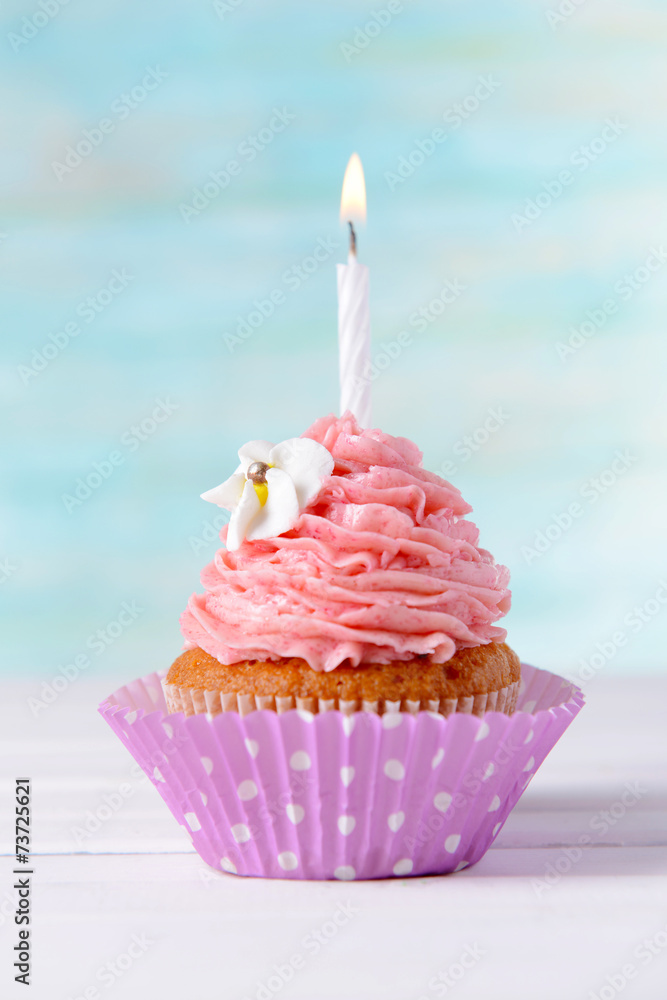 Delicious birthday cupcake on table on light blue background Delicious birthday cupcake on table on light blue background