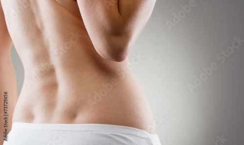 Part of female's back with scoliosis over grey