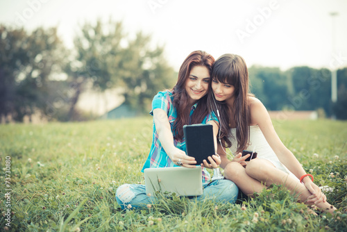 beautiful hipster young women sisters friends using tablet and s