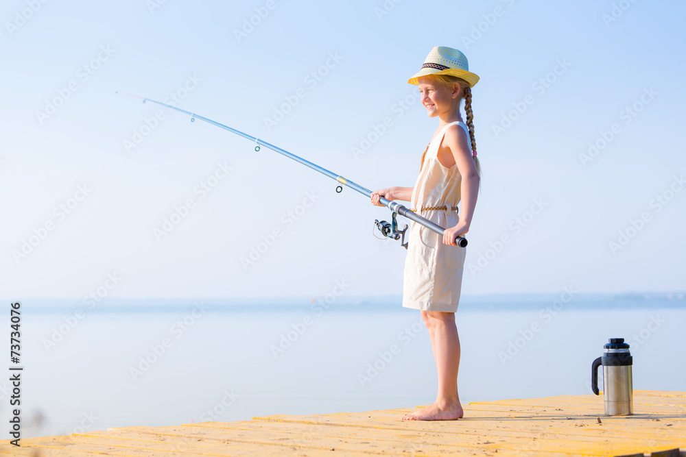 Girl in a dress and a hat with a fishing rod