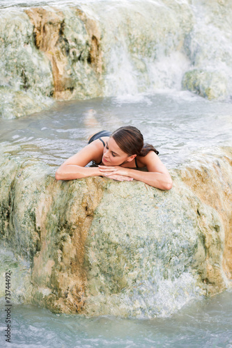 Young woman lying in the natural pool, Saturnia, Italy