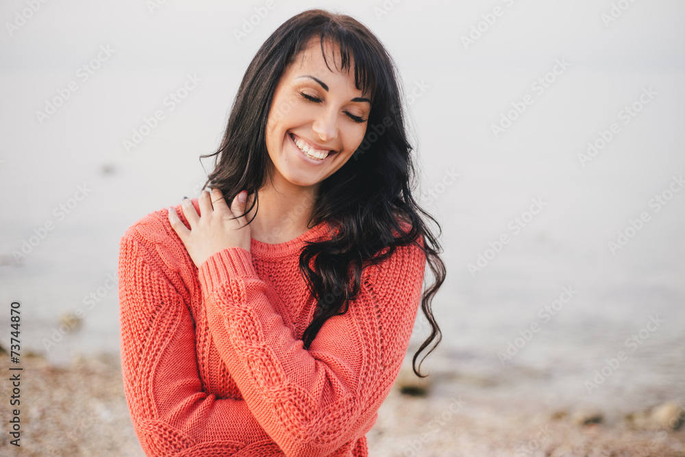 Young woman in a red sweater walking on the beach
