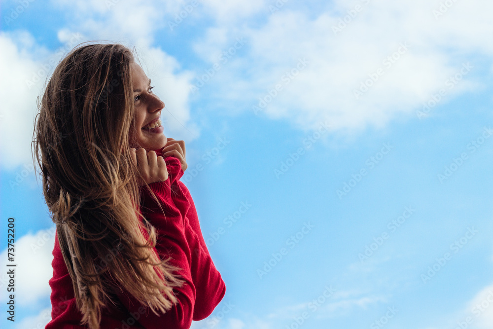 Beautiful smiling young girl, against a sky background