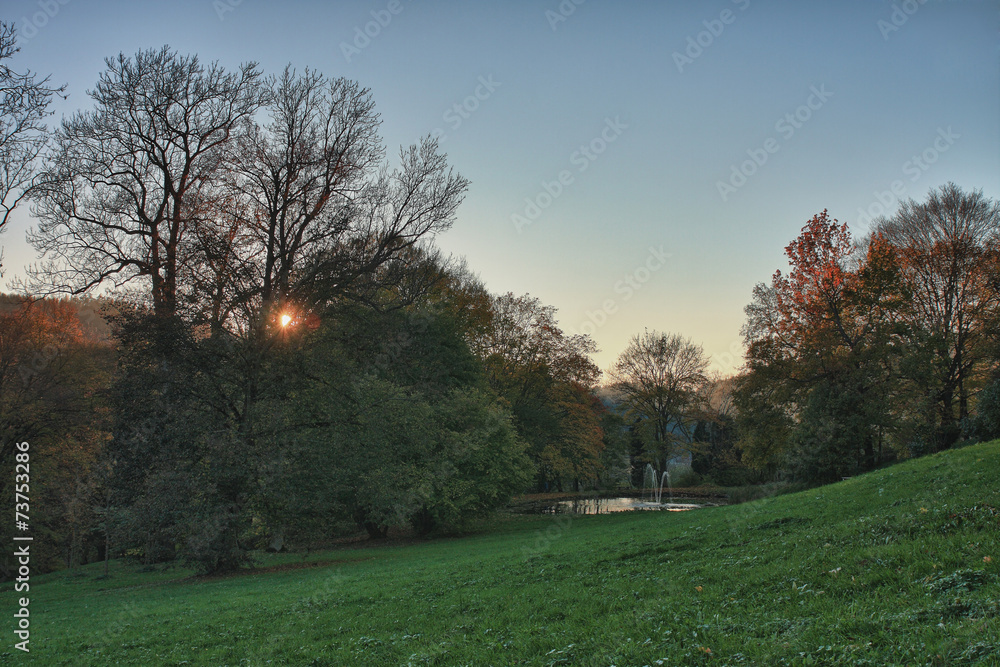 Autumn park and small lake at sunset