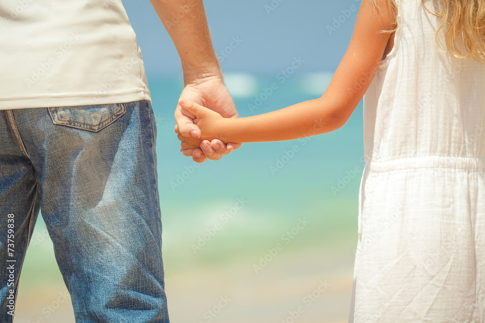 father and daughter standing on the beach at the day time father and daughter standing on the beach at the day time