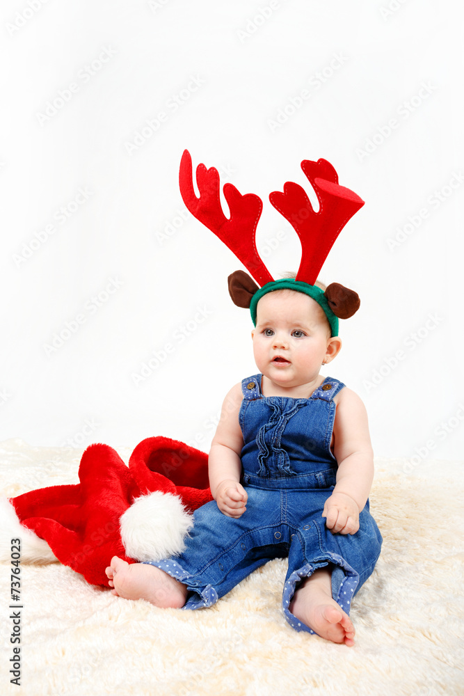 Child girl with Christmas santa hat and reindeer antlers Child girl with Christmas santa hat and reindeer antlers