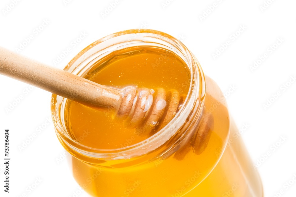 honey jar on white background with wooden honey dipper inside honey jar on white background with wooden honey dipper inside