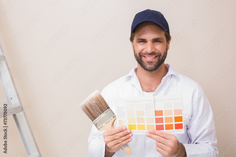 Painter holding a colour chart smiling at camera Painter holding a colour chart smiling at camera
