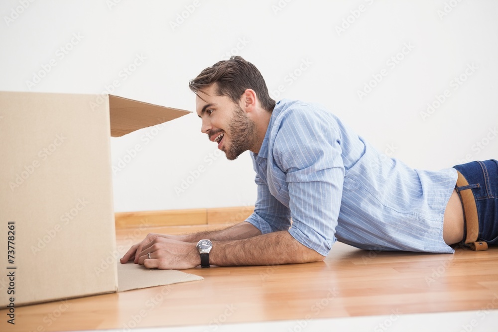 Smiling man looking inside cardboard box Smiling man looking inside cardboard box
