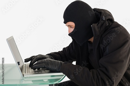 Robber sitting at desk hacking a laptop