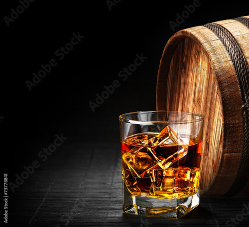 Canvas Print Glass of cognac on the vintage wooden barrel