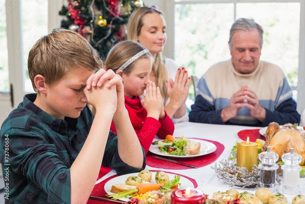 Extended family saying grace before christmas dinner