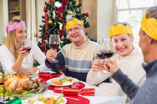 Family in party hat toasting at christmas dinner