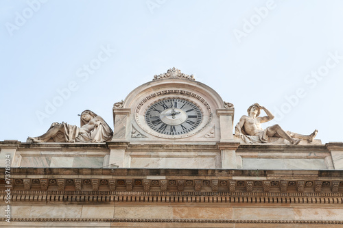 Antique facade with clock and naked sculptures