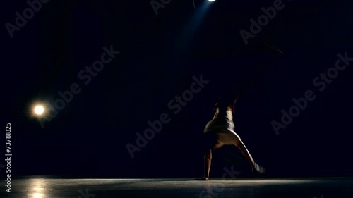 Skilled breakdancer in a dark gymnasium of lights