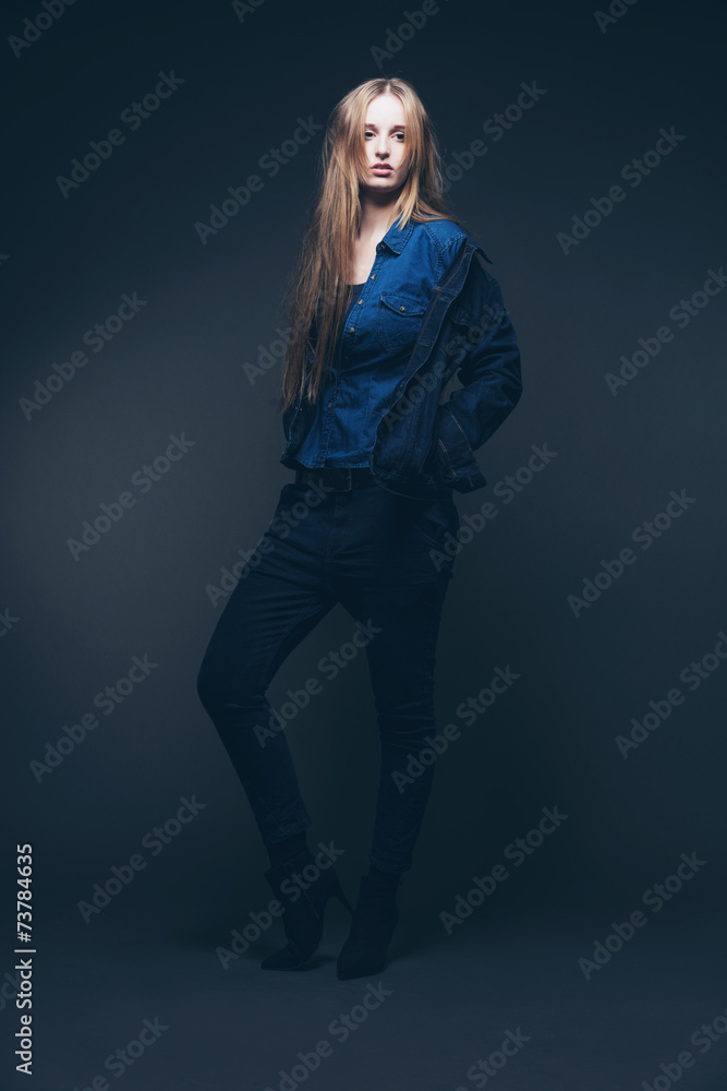 Woman jeans winter fashion. Long blonde hair. Studio shot agains Woman jeans winter fashion. Long blonde hair. Studio shot agains