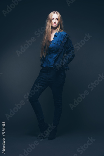 Woman jeans winter fashion. Long blonde hair. Studio shot agains