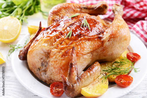 Delicious baked chicken on plate on table close-up