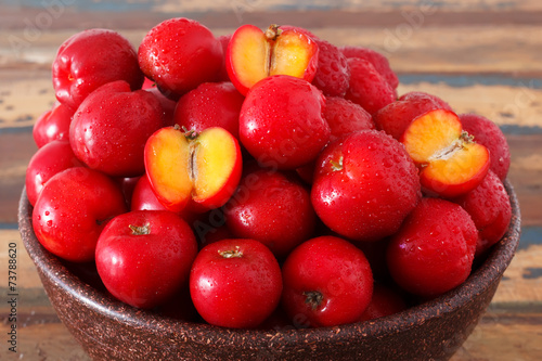 Fotografie Red acerola - malpighia glabra, tropical fruit  in wicker busket