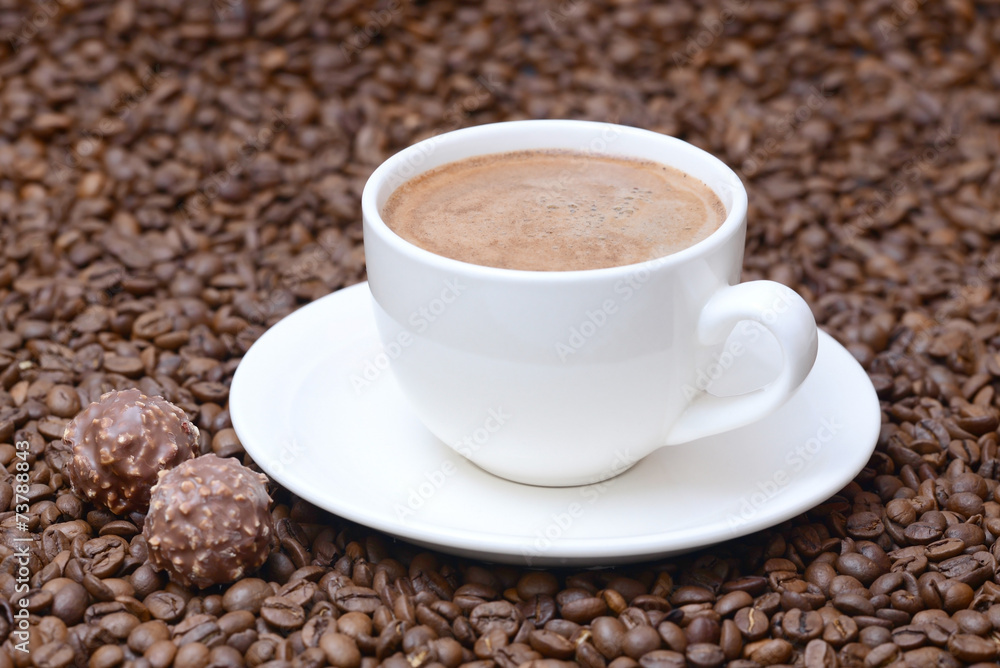 cup of coffee and candies on a coffee beans background cup of coffee and candies on a coffee beans background