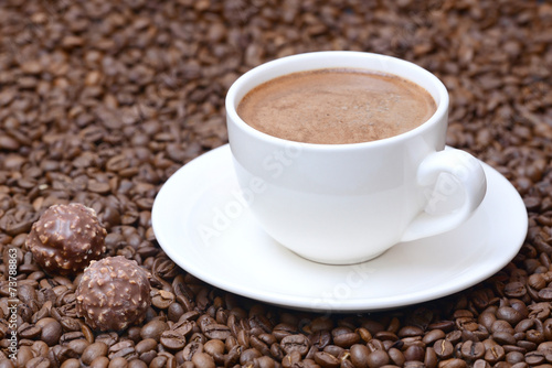 cup of coffee and candies on a coffee beans background