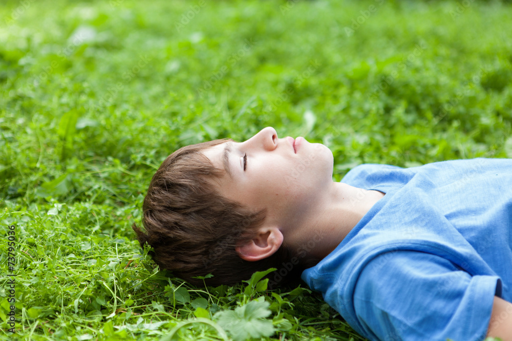 Happy teenager lying on grass in park Happy teenager lying on grass in park
