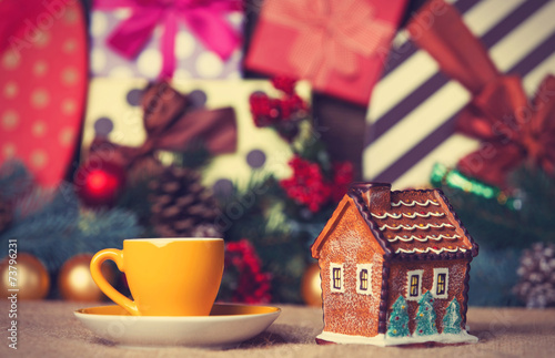 Cup of coffee and christmas house toy on a table