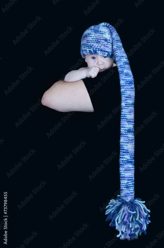 Newborn baby in a long multi-colored hat looking at the camera o