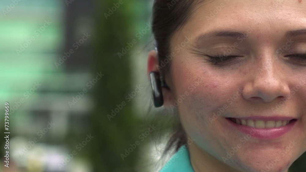 Businesswoman with bluetooth device looking at camera smiling Businesswoman with bluetooth device looking at camera smiling