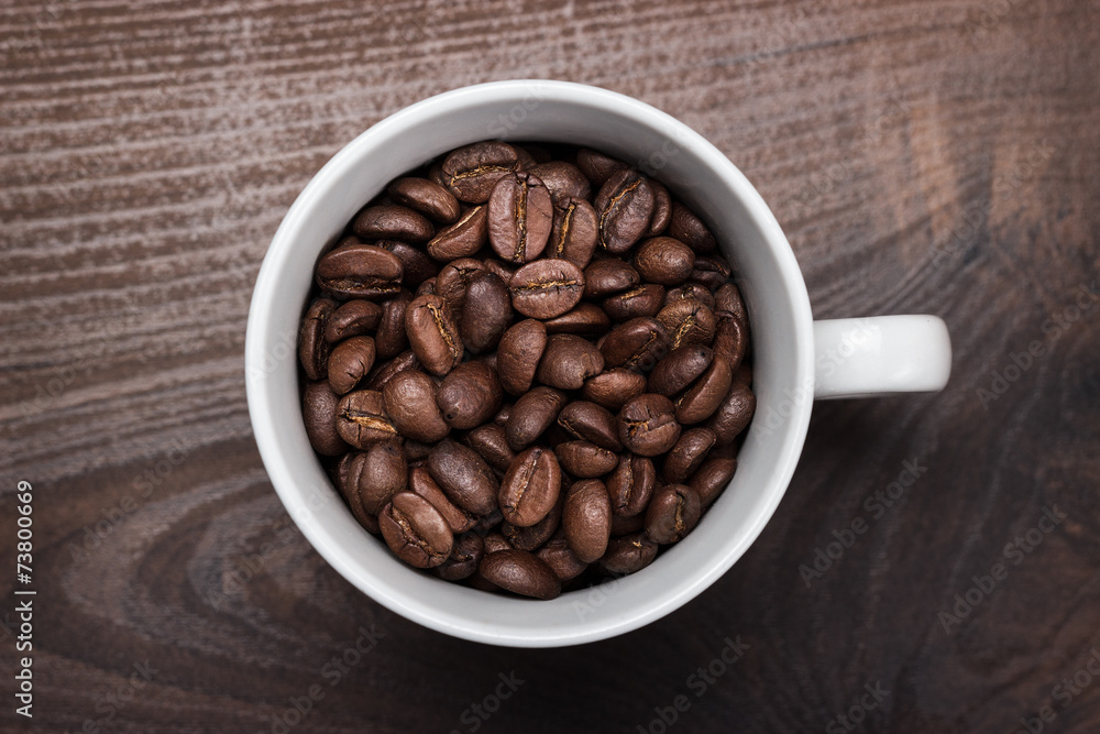 cup of coffee beans on brown wooden background cup of coffee beans on brown wooden background