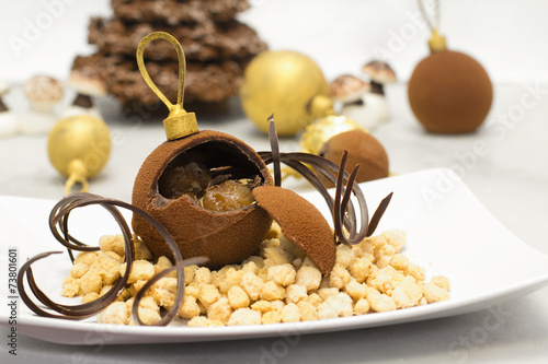 chocolate bauble with glazed chestnut inside against christmas b