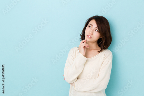 attractive asian woman thinking on blue background