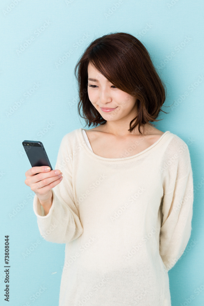 attractive asian woman using smart phone on blue background attractive asian woman using smart phone on blue background