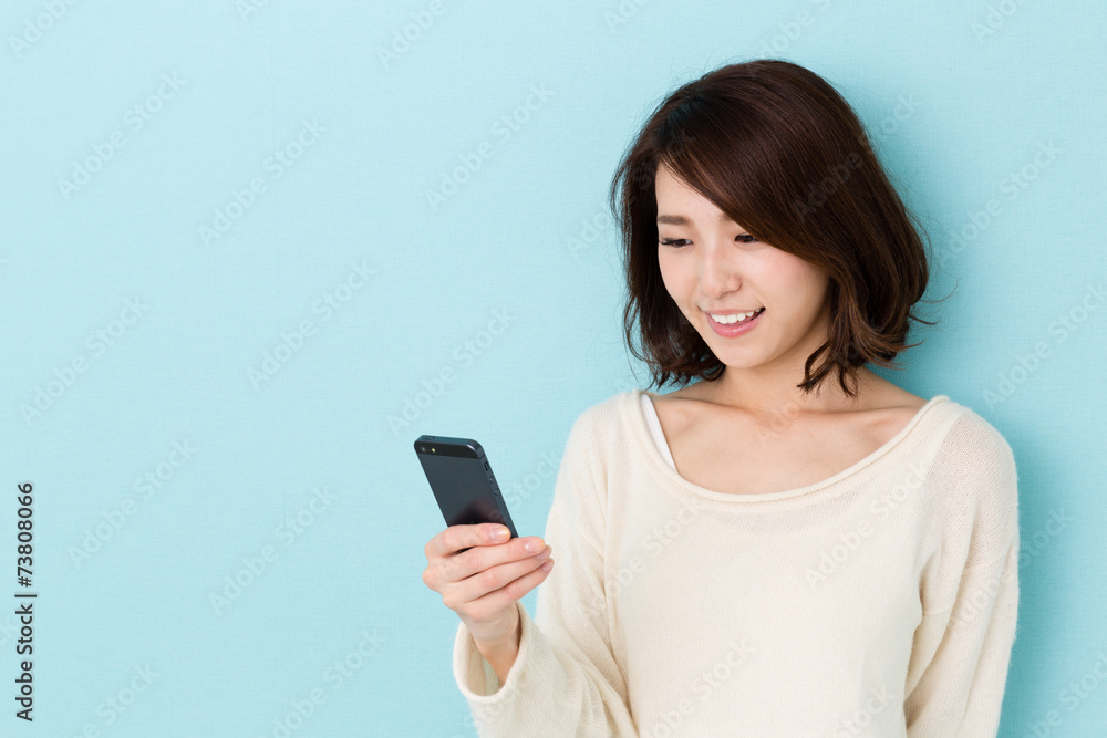 attractive asian woman using smart phone on blue background attractive asian woman using smart phone on blue background