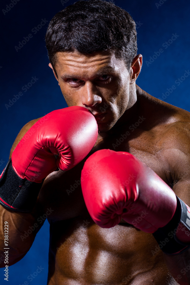 Strong athletic man with boxing gloves on a blue background