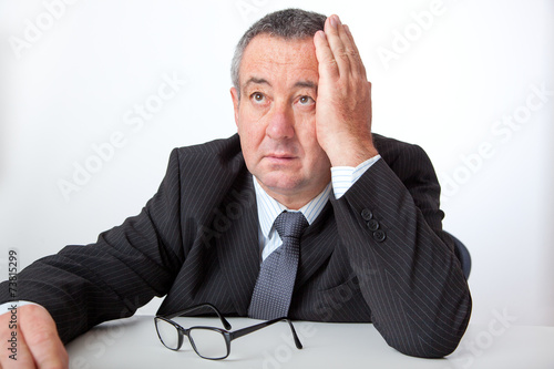 Businessman sitting at desk, holding his hand to his head photo