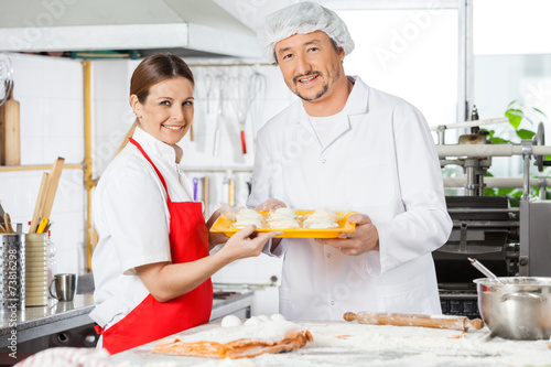 Confident Chefs Holding Pasta Tray In Kitchen