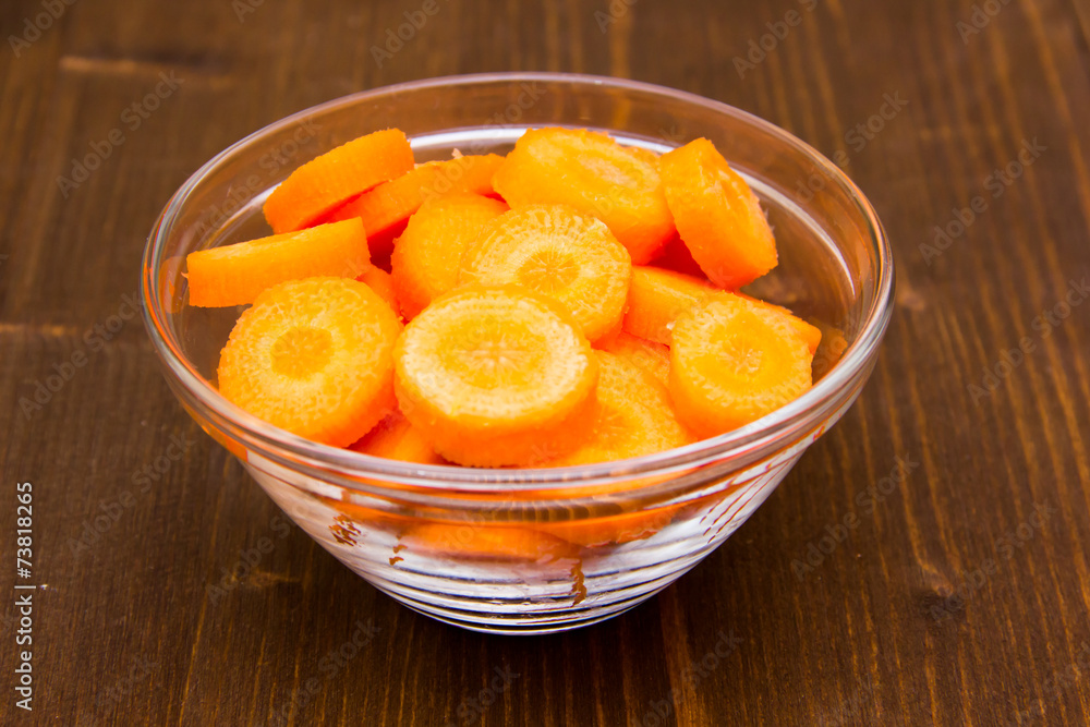 Carrot slices on bowl on wooden table Carrot slices on bowl on wooden table