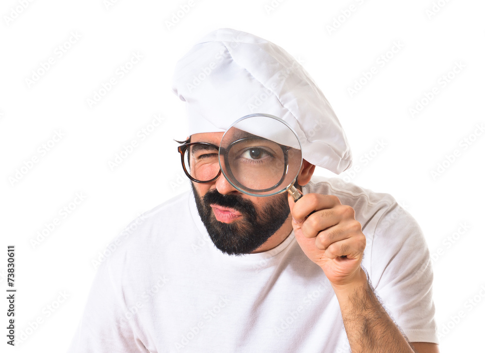Chef with magnifying glass over white background Chef with magnifying glass over white background