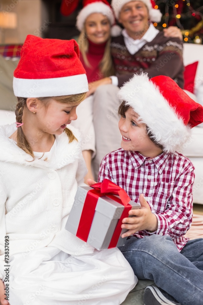 Little siblings opening a gift in front of their parents Little siblings opening a gift in front of their parents