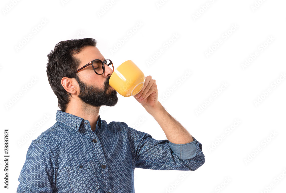 Fototapeta premium Young hipster man drinking coffee over white background
